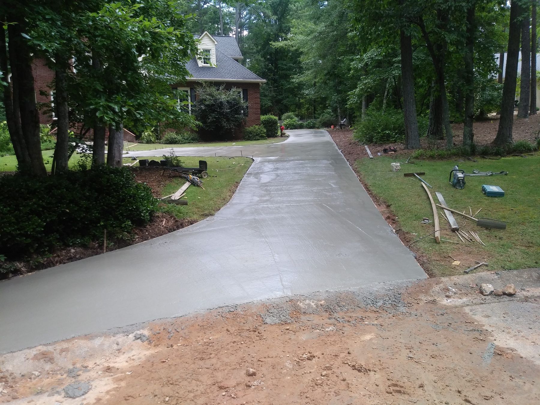 Finished-looking concrete driveway curving through a wooded residential lot