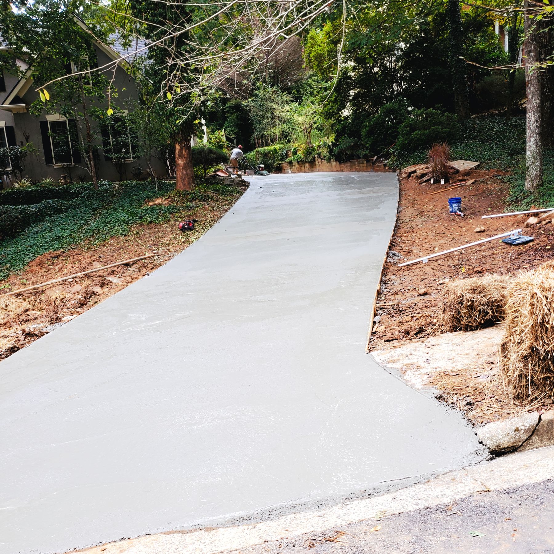 Fresh concrete driveway still in the forms, winding up a wooded residential lot — Hugh’s own job photo